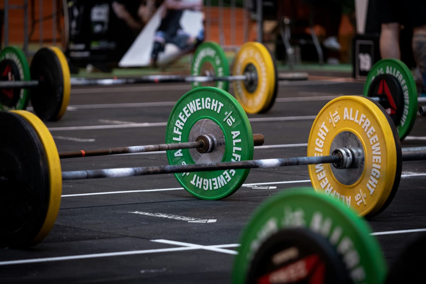 Green and yellow barbell plates on the floor of a CrossFit competition