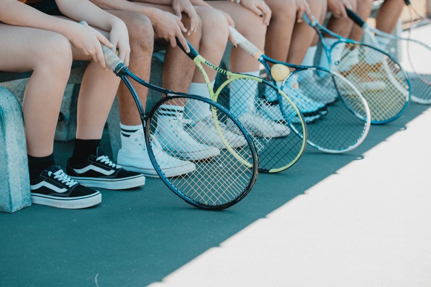 Group of players sitting courtside with their tennis rackets