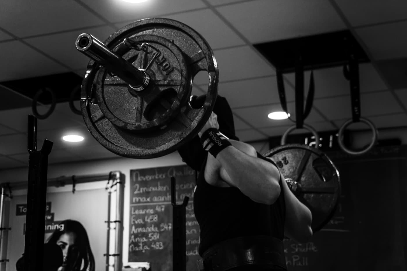 Black and white photo of an athlete holding a loaded barbell in a CrossFit box